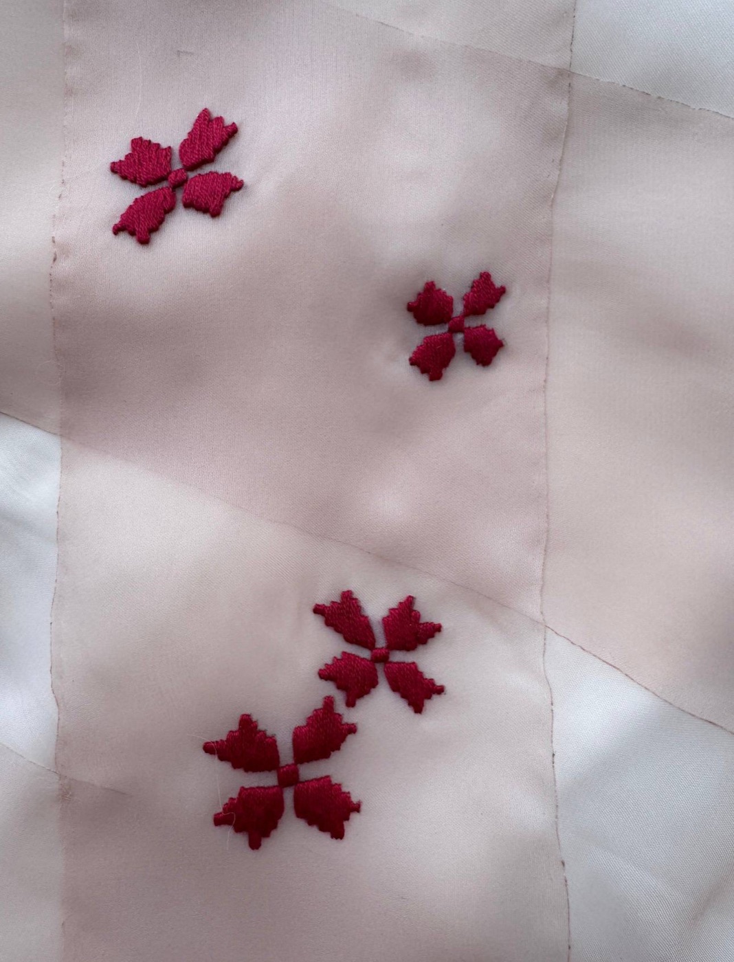 Detail of embroidered crimson flowers on layered organza