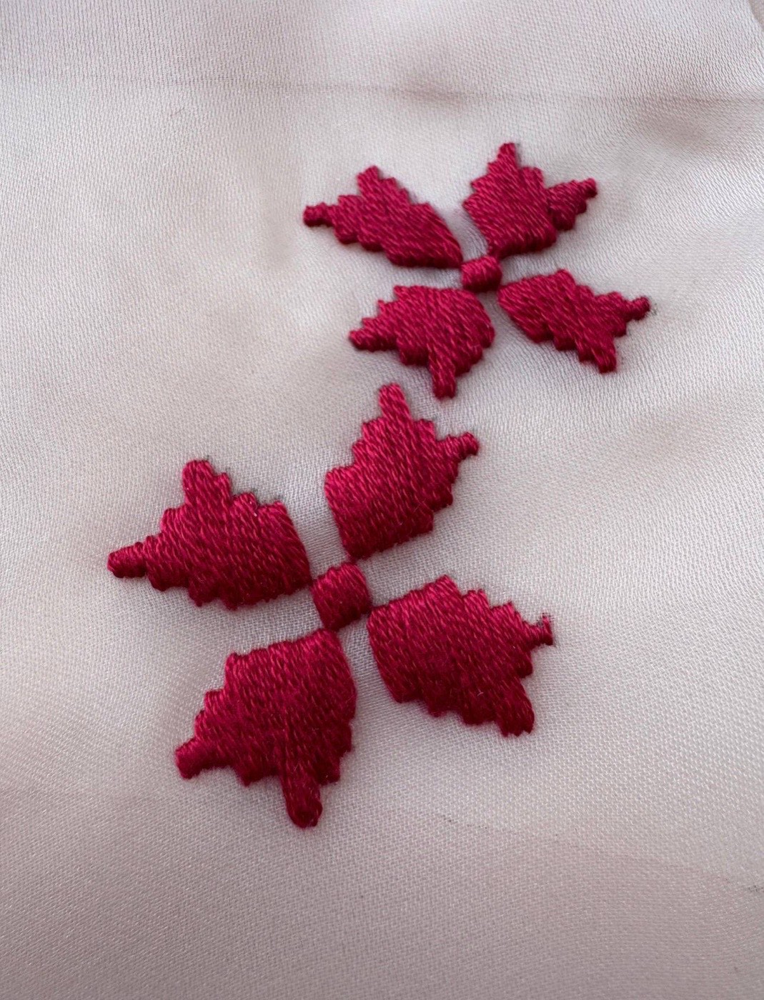Detail of The Tibetan Knot in Ukrainian Thread — crimson cross-stitch flowers on organza